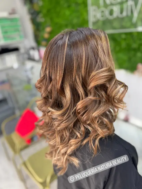 Melena castaña con ondas y reflejos caramelo, vista de espaldas